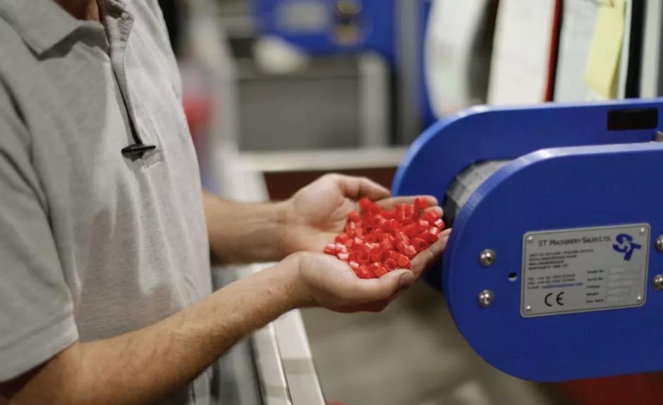 Man inspecting red caps coming off a production line 