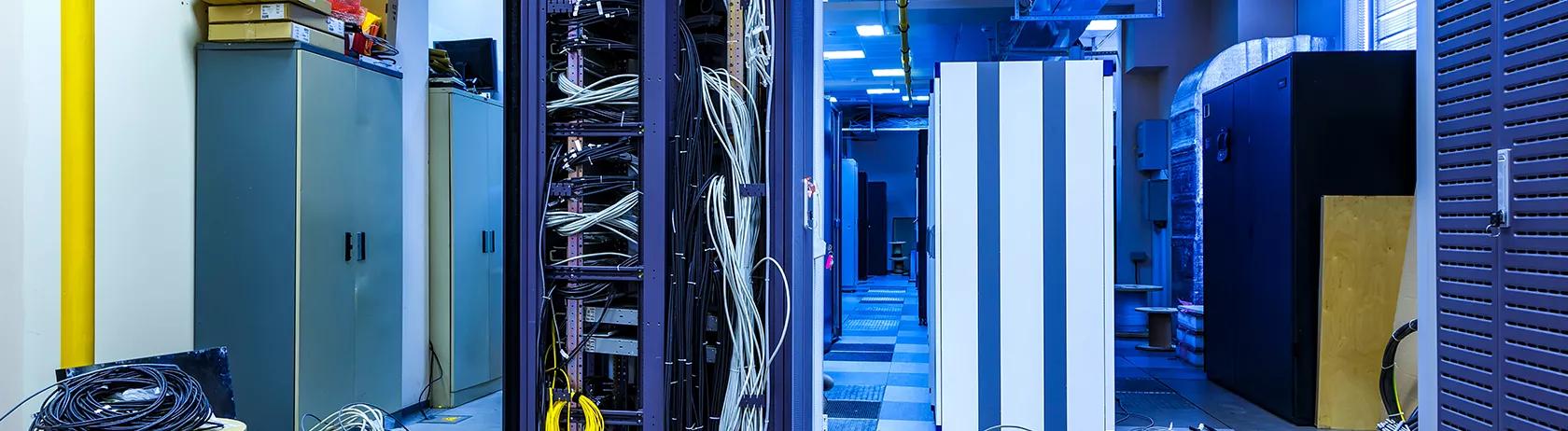 Server room with lots of disordered wiring  around data centre server cabinets  