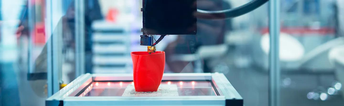 3D printing machine making a red plastic cup