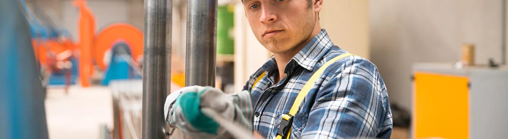 Homme tenant un manchon de câble tressé dans une usine