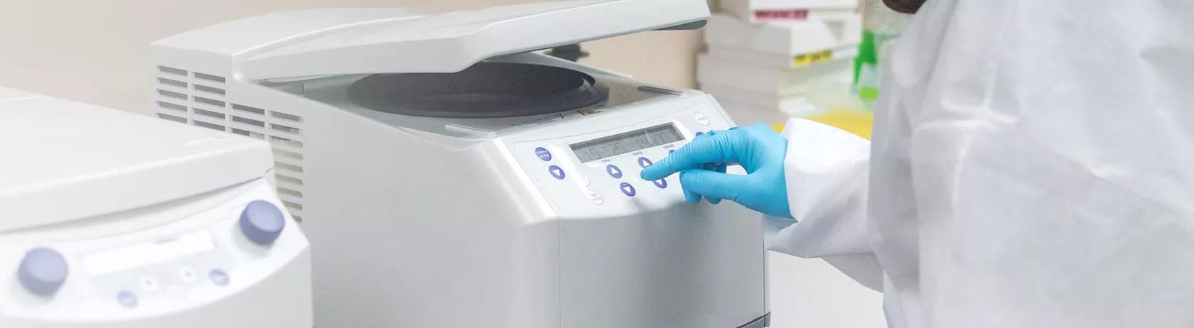 Woman operating a clinical analyser in laboratory