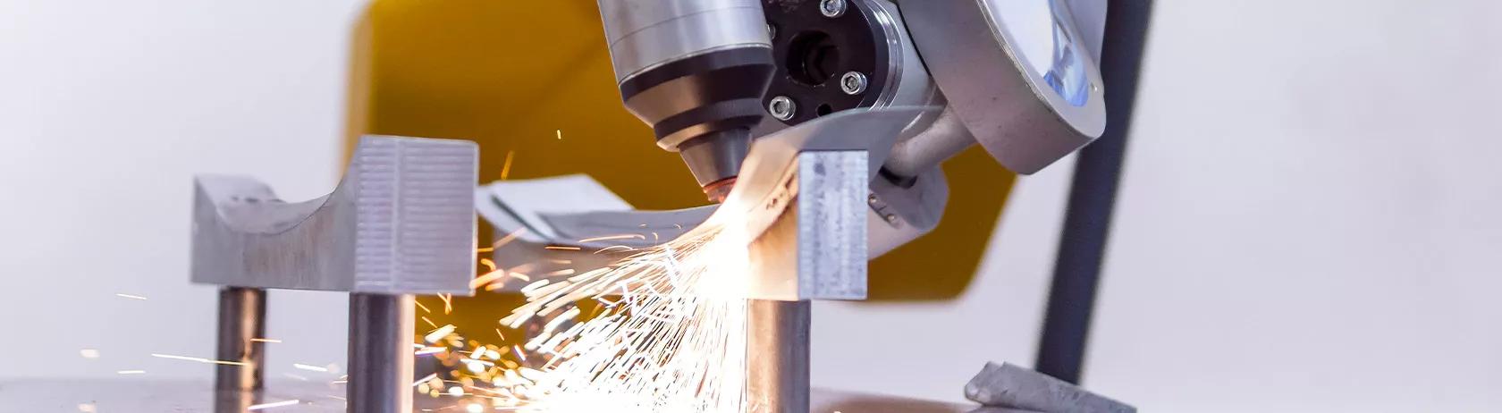 Robotic arm laser cutting metal with sparks