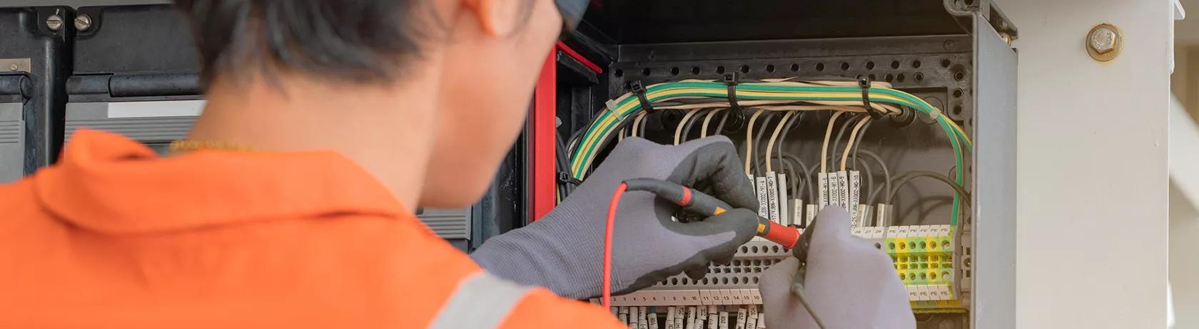 Electrical technician examining a cable junction box using zip tie cable management