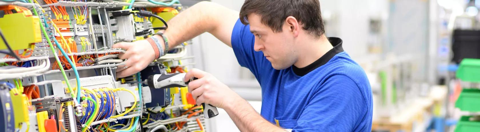 Worker in an industrial company inspecting wires and assembling electronic components