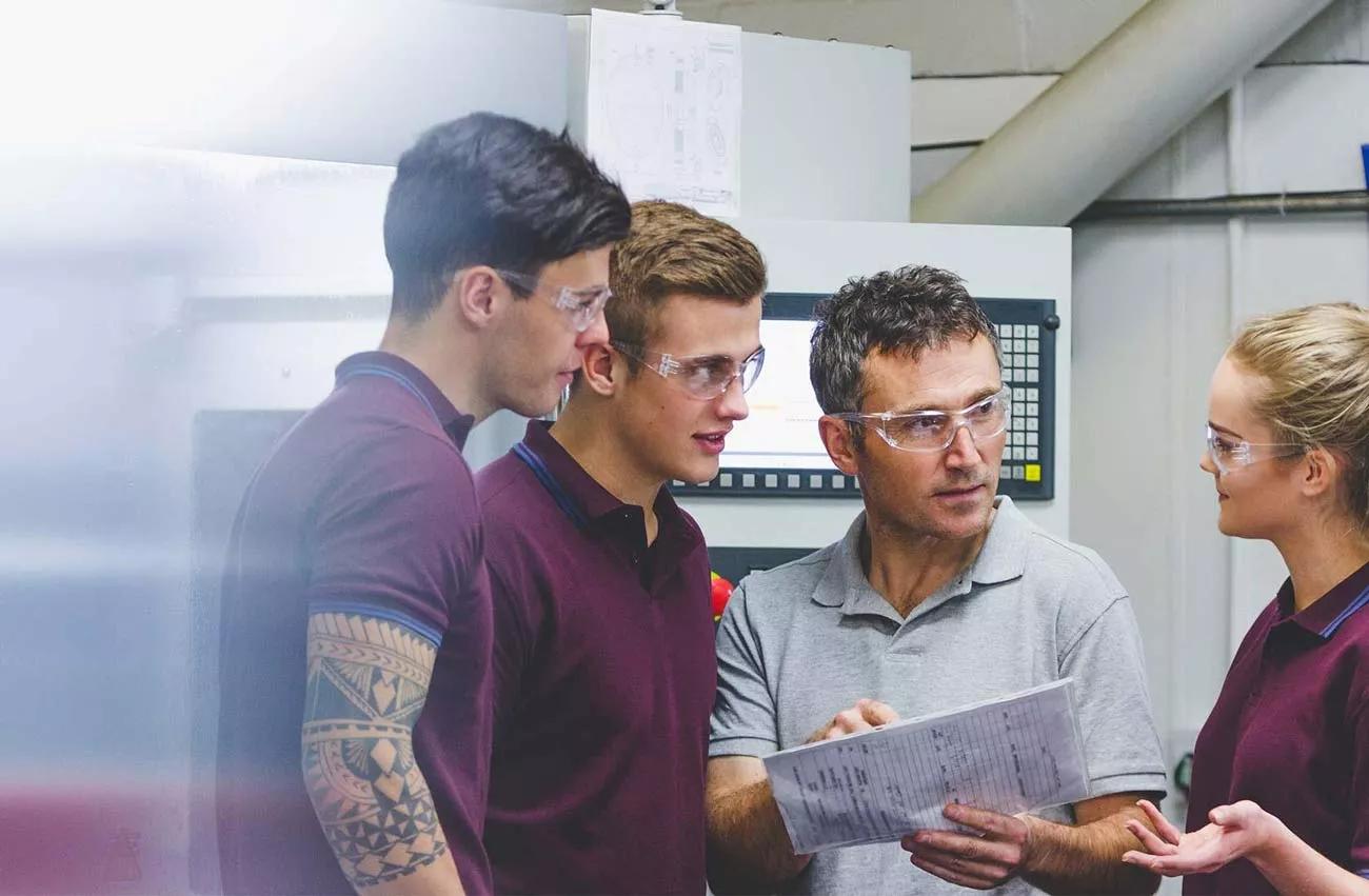 Ingénieur discutant avec de jeunes stagiaires portant des lunettes de sécurité