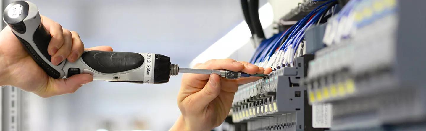 Engineer fixing screw into electrical cabinet