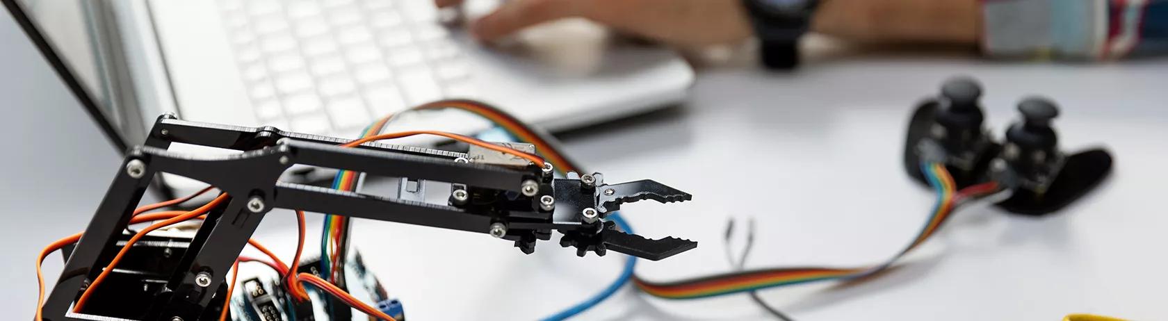 Un tecnico che programma un braccio robotico su un computer