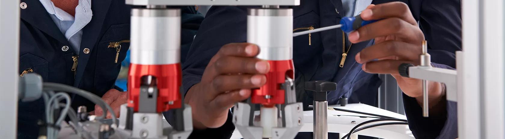 Engineer and apprentice working on a machine in a factory