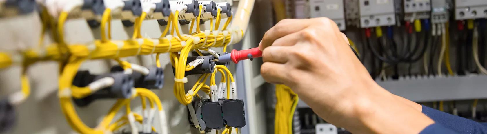 Electrician testing electric cabling in control panel