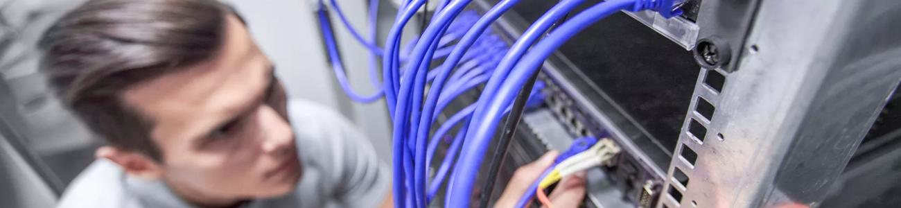 Homme travaillant dans une salle de serveurs réseau avec des câbles à fibre optique 
