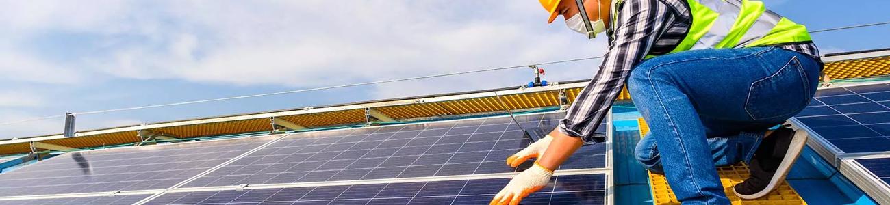 Worker in high visibility jacket and hard hat fitting solar panels