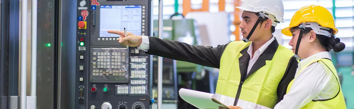 Two people in hi viz looking at machine