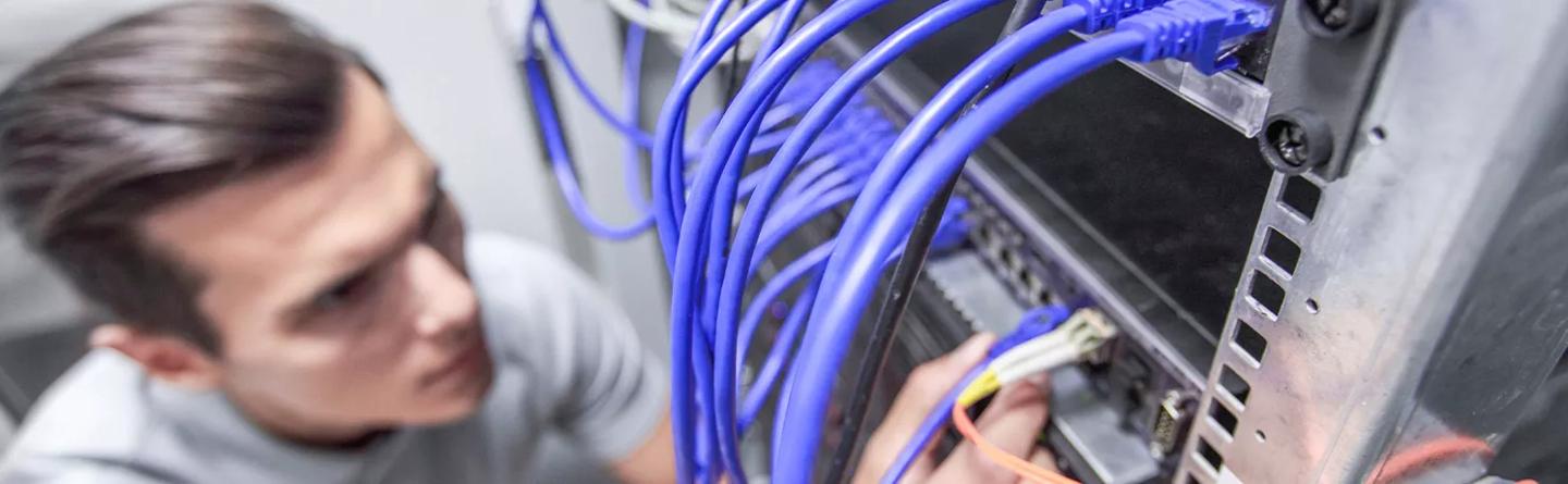Man working in network server room with fibre optic cables