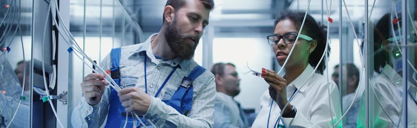 Ingenieros en un centro de datos examinando la protección de la funda de gestión de cableado en hileras de bastidores de servidores