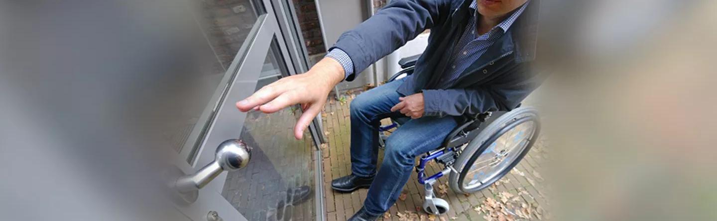 man in wheelchair reaching for door 